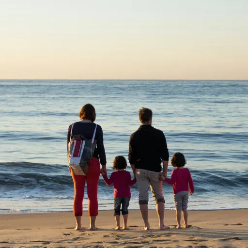 Famille de quatre personnes face à la mer sur une plage au coucher du soleil