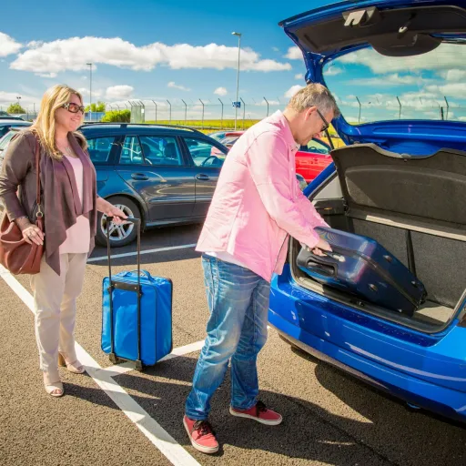 Couple chargeant ses valises dans le coffre de la voiture avant un départ en vacances