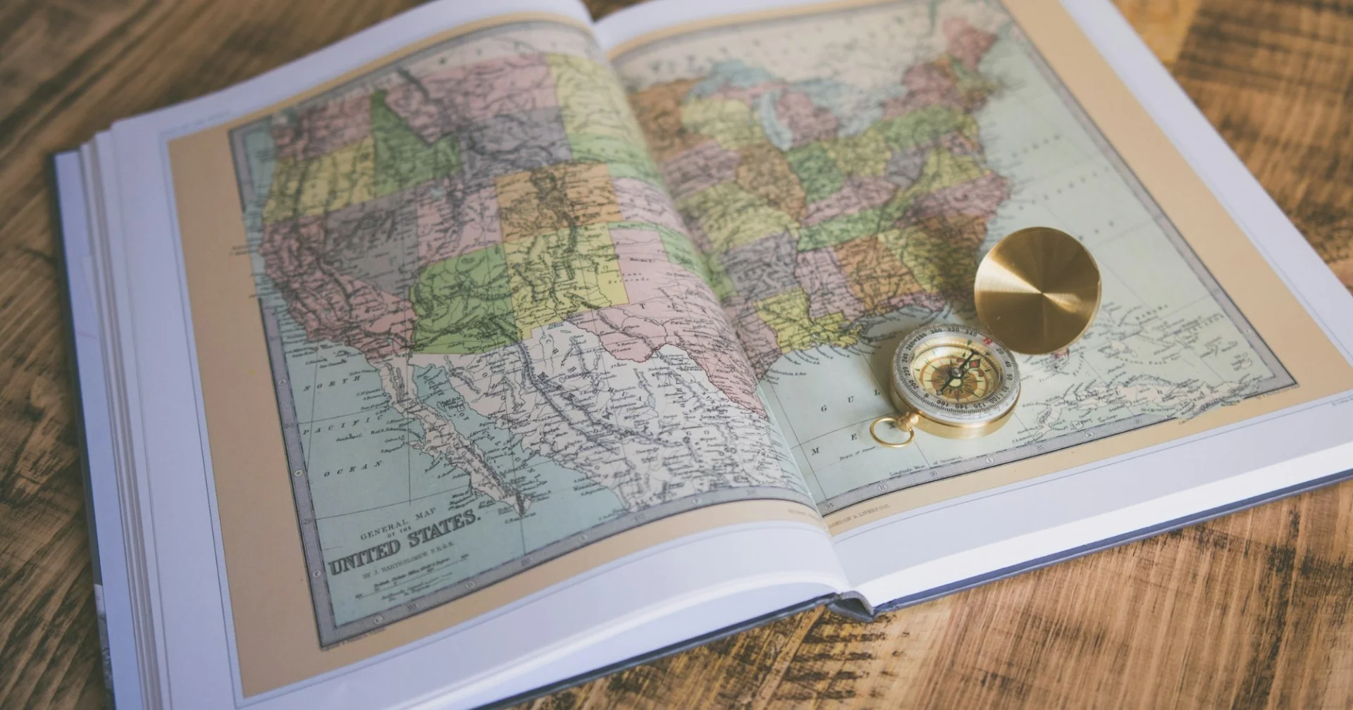 Atlas de voyage ouvert avec une boussole posée dessus